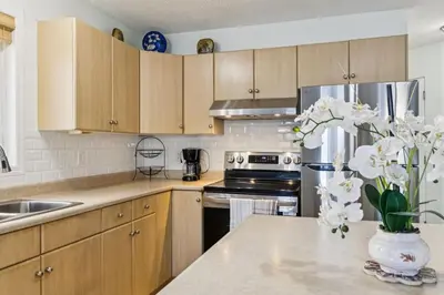 a kitchen with wooden cabinets and a vase of flowers on a counter at Renovated Cozy Family Home Spacious, Modern in Edmonton