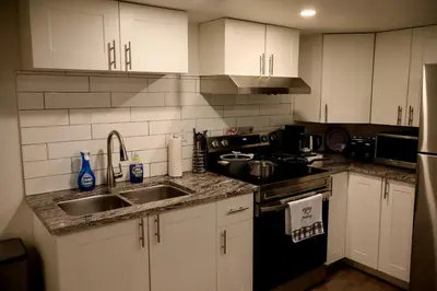 a kitchen with white cabinets and a sink and a stove at Cozy and Private Guest Suite in West Edmonton in Edmonton