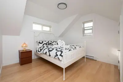 a white bedroom with a bed and a wooden floor at Private 2BR 2Bath Suite - Sunset Vancouver in Vancouver