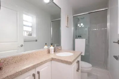 a white bathroom with a sink and a shower at Private 2BR 2Bath Suite - Sunset Vancouver in Vancouver