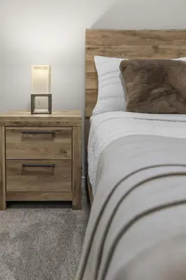 a bedroom with a bed and a nightstand with a lamp at Private Guest Suite in SE Calgary 5 minutes to South Health Campus & Seton YMCA in Calgary