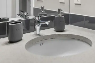 a bathroom sink with two faucets and two cups at Private Guest Suite in SE Calgary 5 minutes to South Health Campus & Seton YMCA in Calgary