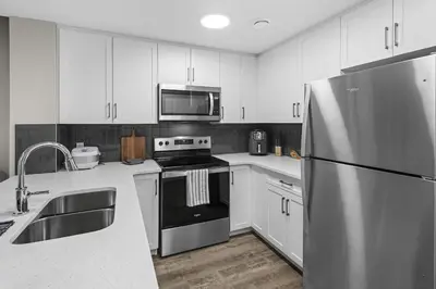 a kitchen with white cabinets and a stainless steel refrigerator at Private Guest Suite in SE Calgary 5 minutes to South Health Campus & Seton YMCA in Calgary