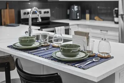 a kitchen counter with plates and glasses and a sink at Private Guest Suite in SE Calgary 5 minutes to South Health Campus & Seton YMCA in Calgary