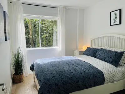 a white bedroom with a bed and a window at Lynn Canyon Forest Retreat in North Vancouver