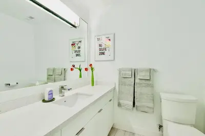 a white bathroom with a sink and a toilet at Lynn Canyon Forest Retreat in North Vancouver