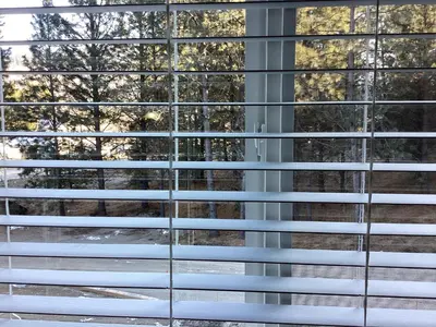 a window with venetian blinds looking out at trees at The Cozy Nook in Grand Forks