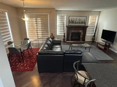 a living room with a black leather couch and a table at Peace Home in Calgary