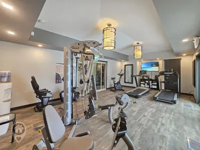 a gym with several treadmills and exercise bikes at Bighorn Meadows Condos by StayIn in Radium Hot Springs
