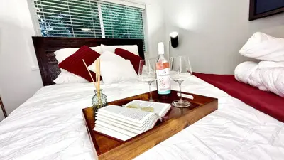 a bed with a wooden tray with books and wine glasses at Emerald 3Bed 1bath Rancher 2C-D EvEs Spa BBQ RKE in Langley