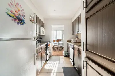 a kitchen with a stainless steel refrigerator and wooden cabinets at Central Vancouver 1BR Close to Transit in Vancouver