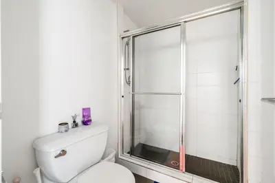 a white bathroom with a shower and a toilet at Central Vancouver 1BR Close to Transit in Vancouver