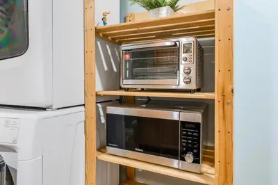 a microwave and a toaster oven on a wooden shelf at Comfortable Westside Vancouver Stay in Vancouver