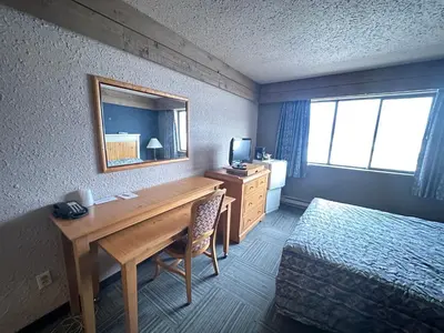 a hotel room with a desk and a bed and a mirror at Logan Lake Hotel in Logan Lake