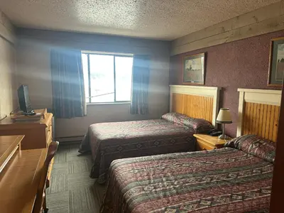 a hotel room with two beds and a window at Logan Lake Hotel in Logan Lake