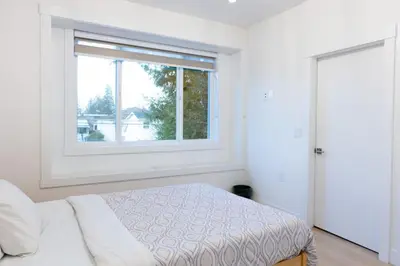 a white bedroom with a bed and a window at Elegant Stylish Modern Residence in Vancouver