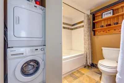 a bathroom with a washing machine and a toilet at Foxglove 22 by Outpost Whistler in Whistler