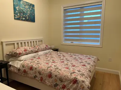 a bedroom with a bed and a window with a bedspread at SixPine - New 2Br Suite in Vancouver