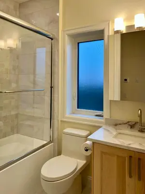 a bathroom with a toilet and a shower and a window at SixPine - New 2Br Suite in Vancouver