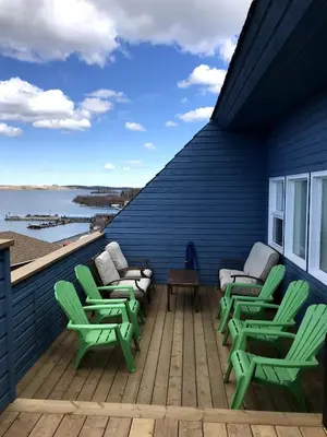 a deck with green chairs and chairs on a blue house at See Aurora and lake from EVERY room - 2bd 2bth in Yellowknife