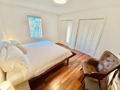 a bedroom with a bed and a chair and a window at Aurora views from 2 br apartment by lake in Yellowknife