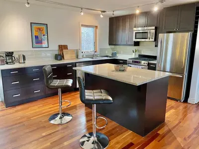 a kitchen with a large island with two bar stools at Aurora views from 2 br apartment by lake in Yellowknife