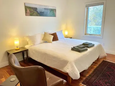 a bedroom with a bed with a chair and a window at Aurora views from 2 br apartment by lake in Yellowknife