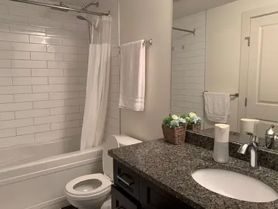 a bathroom with a sink and a toilet and a tub at Modern 2BR Retreat Near West Edmonton Mall in Edmonton