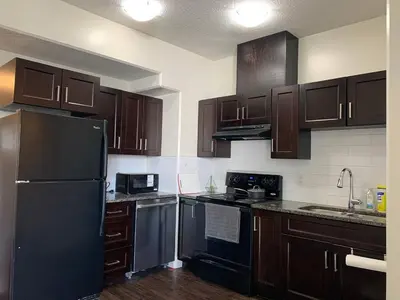 a kitchen with wooden cabinets and a black refrigerator at Modern 2BR Retreat Near West Edmonton Mall in Edmonton