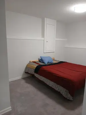 a bed in a white room with a red blanket at Aeropuerto basement in Calgary