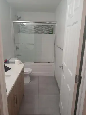 a white bathroom with a toilet and a shower at Aeropuerto basement in Calgary