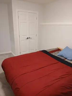 a bedroom with a red bed with a white door at Aeropuerto basement in Calgary