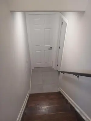 a hallway with a white door and a wooden floor at Aeropuerto basement in Calgary