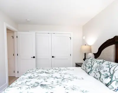 a white bedroom with a bed and white cabinets at Cozy Corner on Trumpeter in Colwood