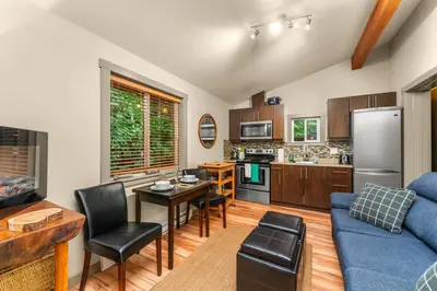 a living room with a blue couch and a kitchen at JDF Waystation with Bunkhouse - Pet Friendly - sleeps 6 in Port Renfrew