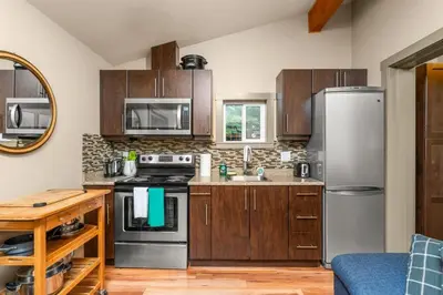 a kitchen with wooden cabinets and stainless steel appliances at JDF Waystation with Bunkhouse - Pet Friendly - sleeps 6 in Port Renfrew