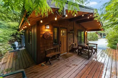 a wooden deck with a table and chairs on it at JDF Waystation with Bunkhouse - Pet Friendly - sleeps 6 in Port Renfrew