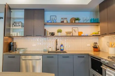 a kitchen with gray cabinets and a counter top at Brand New Canmore Condo by Canadian Rockies Vacation Rentals in Canmore