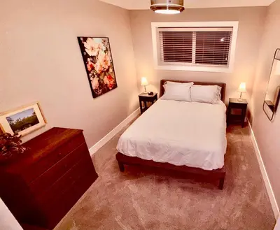 a bedroom with a bed and two night stands and a window at Fields & Fences Suite in Maple Ridge District Municipality