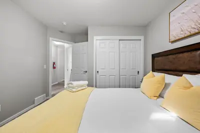 a bedroom with a large white bed with yellow pillows at Family 3BR Suite w Kid's Play Tent, FREE Banff Pass, Netflix! in Calgary