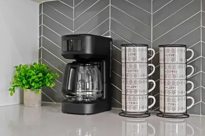 a black coffee maker on a counter with two cups at Family 3BR Suite w Kid's Play Tent, FREE Banff Pass, Netflix! in Calgary