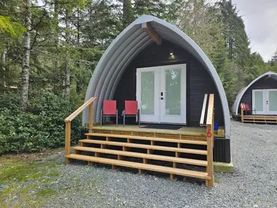 a dome house with a porch and red chairs in it at Pet Friendly cozy cabin getaway with Kitchenette and Private Bath in Port Renfrew