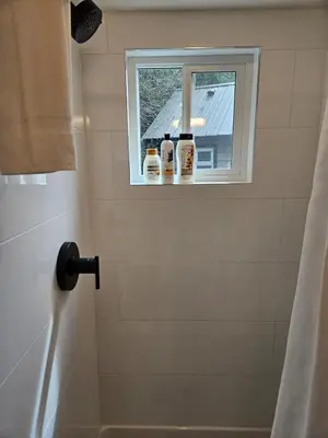 a bathroom with a window with three bottles on a shower curtain at Pet Friendly cozy cabin getaway with Kitchenette and Private Bath in Port Renfrew