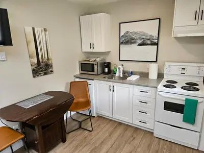 a kitchen with white cabinets and a sink and a stove at Rustic Rainforest Cabin for 2 - Peaceful - Pet Friendly in Port Renfrew