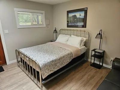 a bed with a metal frame in a bedroom at Rustic Rainforest Cabin for 2 - Peaceful - Pet Friendly in Port Renfrew