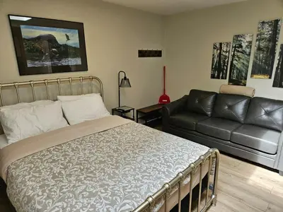 a bedroom with a bed and a couch at Rustic Rainforest Cabin for 2 - Peaceful - Pet Friendly in Port Renfrew