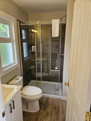 a bathroom with a toilet and a glass shower at Rustic Rainforest Cabin for 2 - Peaceful - Pet Friendly in Port Renfrew