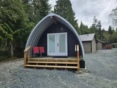 a dome house with a porch and two chairs in it at Stylish Cabin Escape w - Kitchenette & Ensuite Bath in Port Renfrew