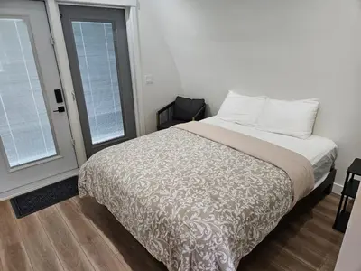 a bedroom with a bed and two windows at Stylish Cabin Escape w - Kitchenette & Ensuite Bath in Port Renfrew