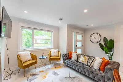a living room with a couch and a clock on the wall at Family friendly Lux house Near University Train Hospital in Edmonton